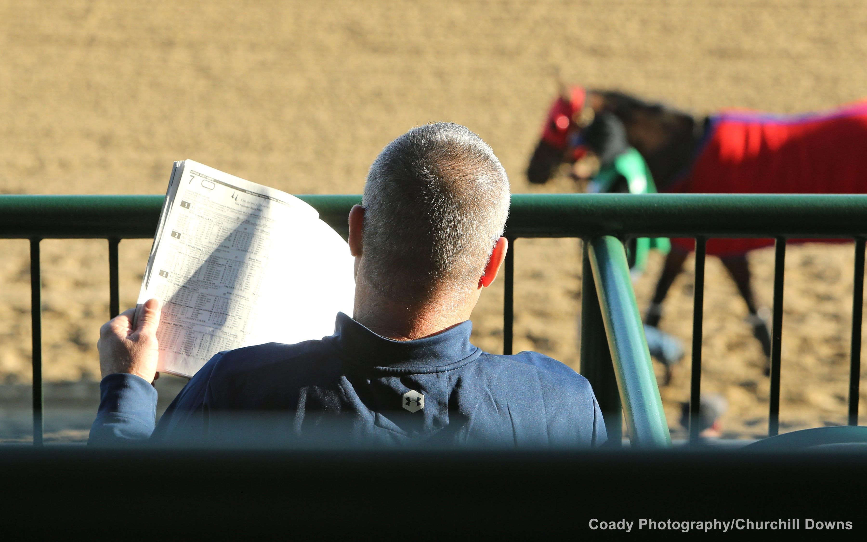 A racing fan peruses the track program at Churchill Downs